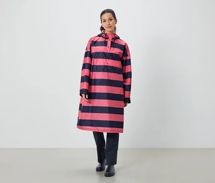 Eine Frau steht und trägt ein gestreiftes, rosa-marineblaues Regenponcho.