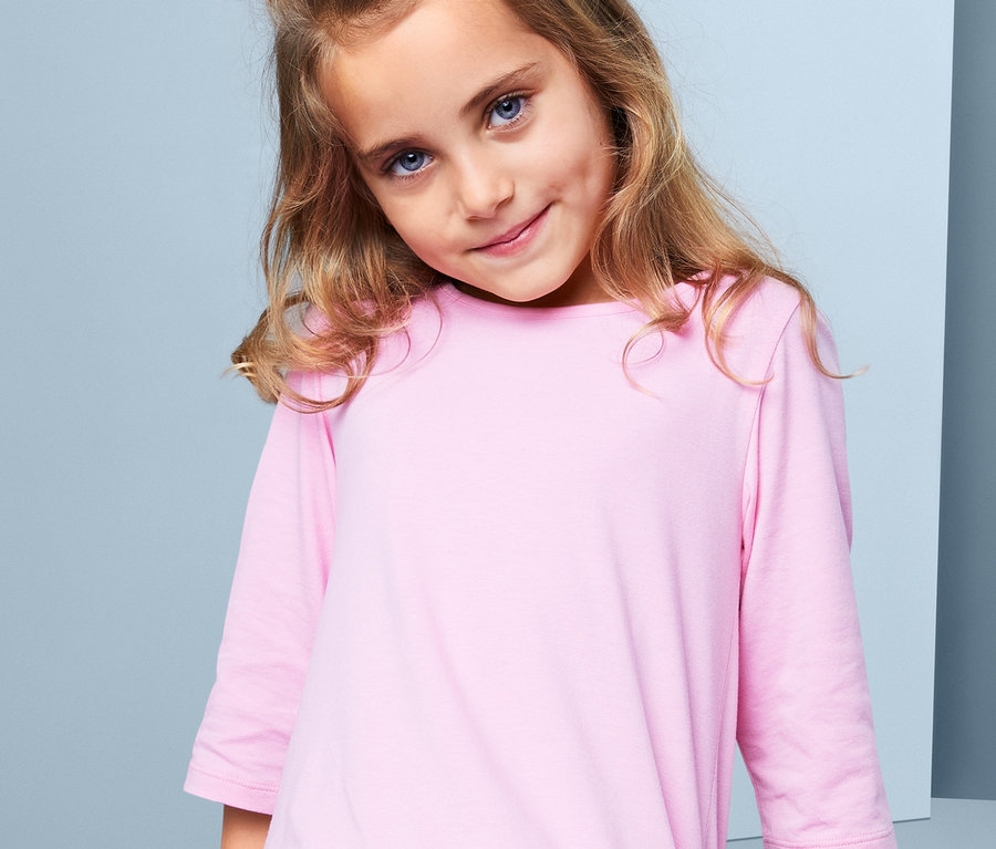 Mädchen mit braunen Haaren und blauen Augen trägt ein rosa Kleid. Im Haar hat sie 3 Haargummis »Scrunchies«.