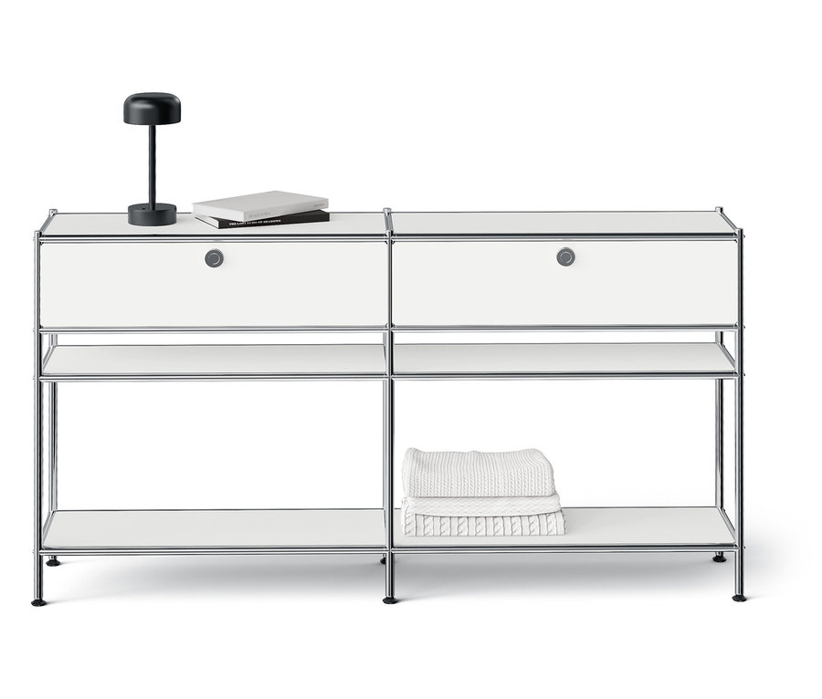 Weißes modulares Aufbewahrungssystem mit zwei Schubladen, offenen Regalen und einer Lampe oben drauf.