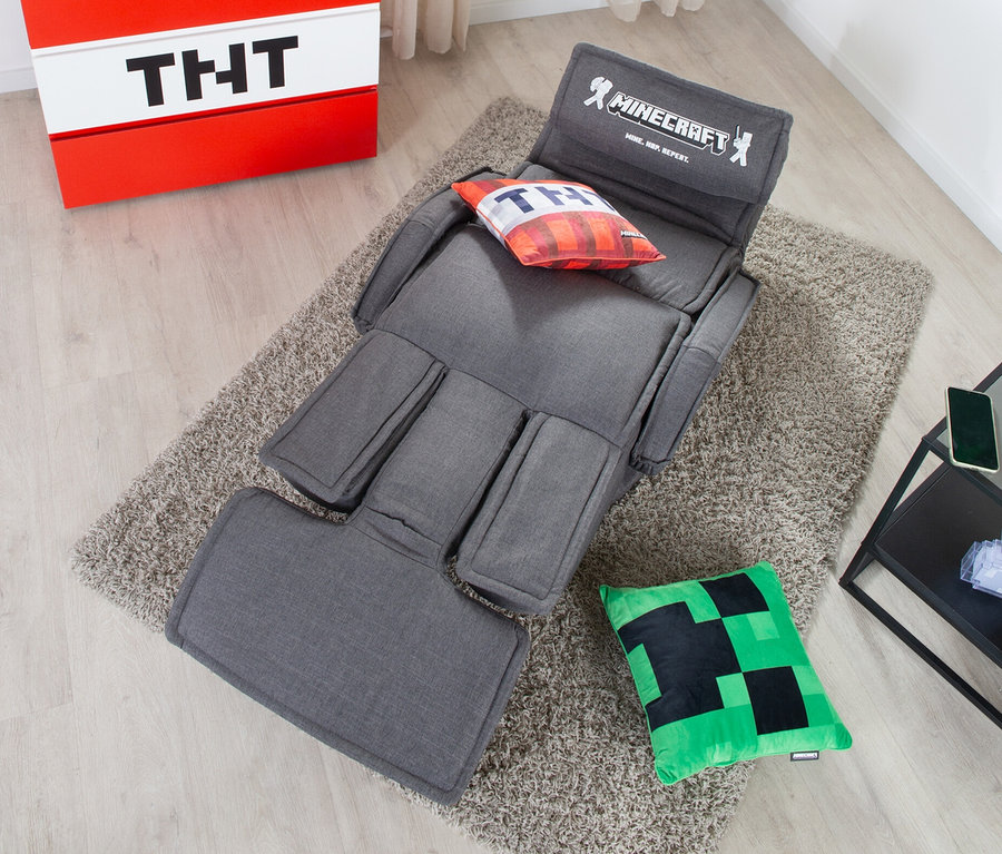 Grauer roba Minecraft Loungesessel mit Beinen und Armlehne auf Teppich, neben rotem Nachttisch mit TNT-Motiv.