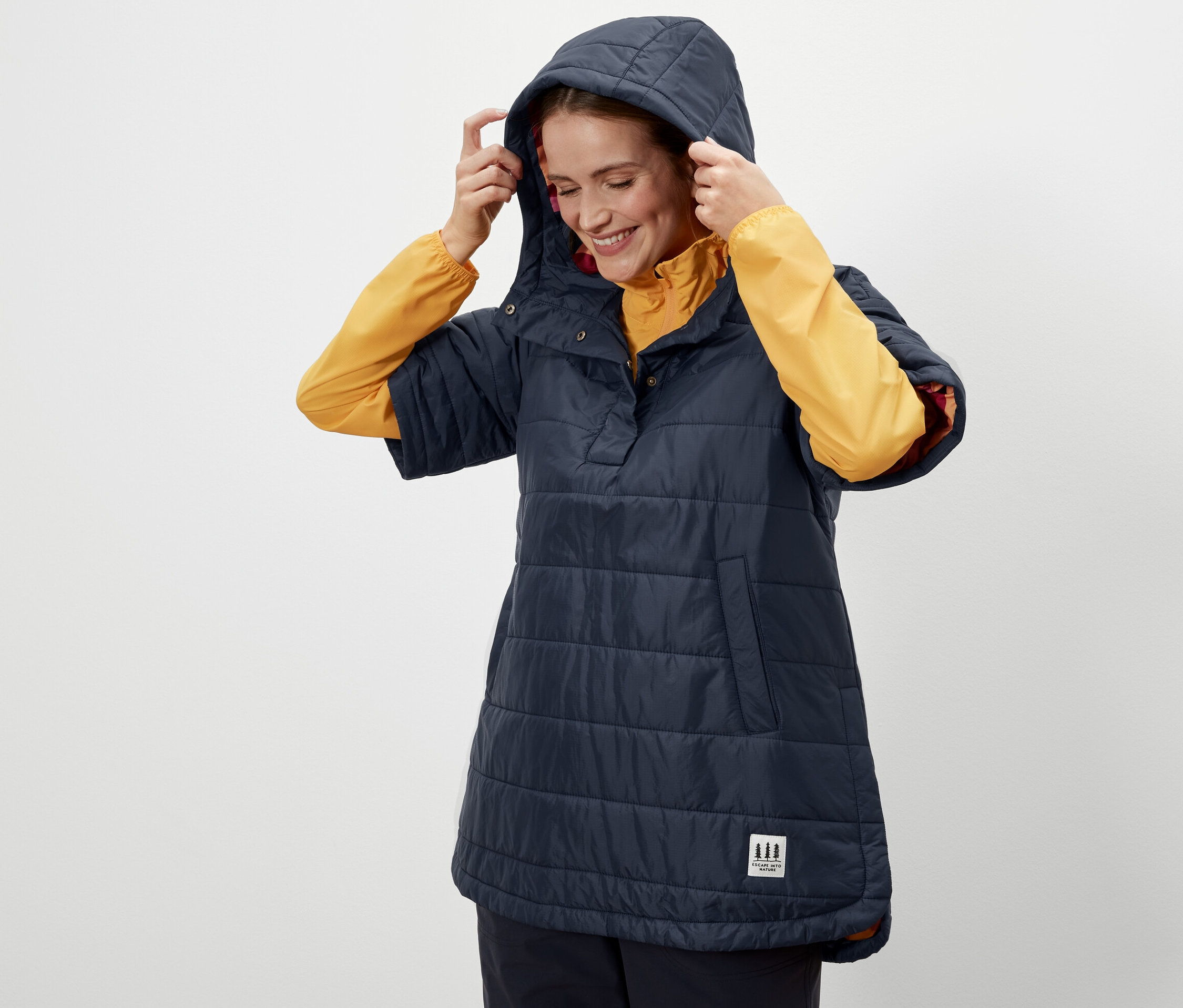 Frau setzt die Kapuze eines Outdoor-Ponchos auf.