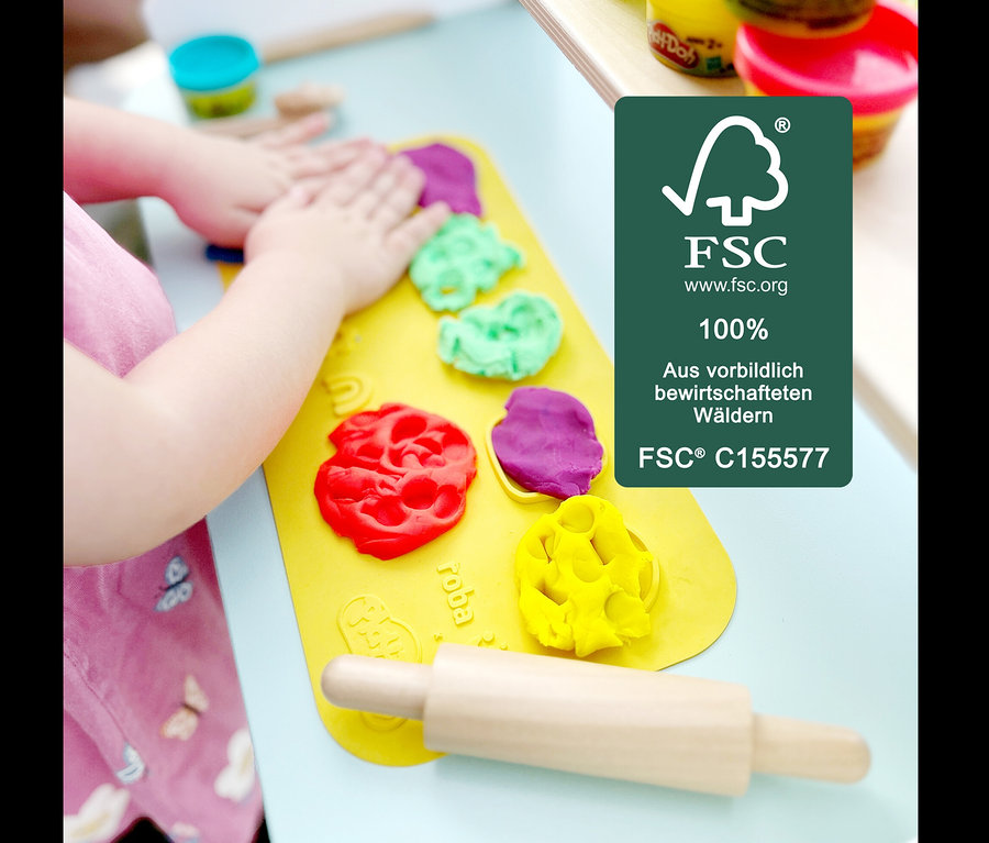 Kind formt Knete von roba x Play-Doh Eisstand auf einer gelben Unterlage.