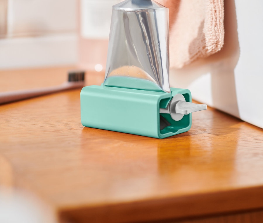 Eine silberne Tube in einem blauen Halter steht auf einer Holzoberfläche.