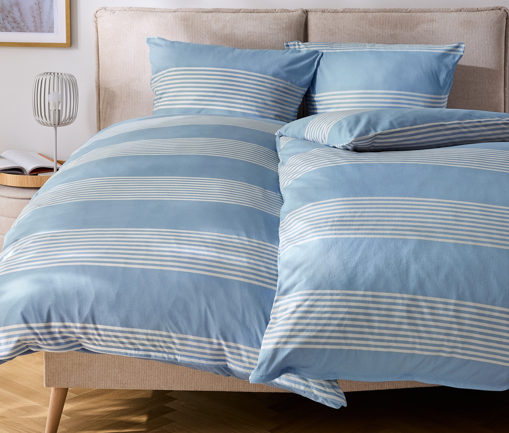 Bett mit blau-weiß gestreifter Bettwäsche und Kissen.