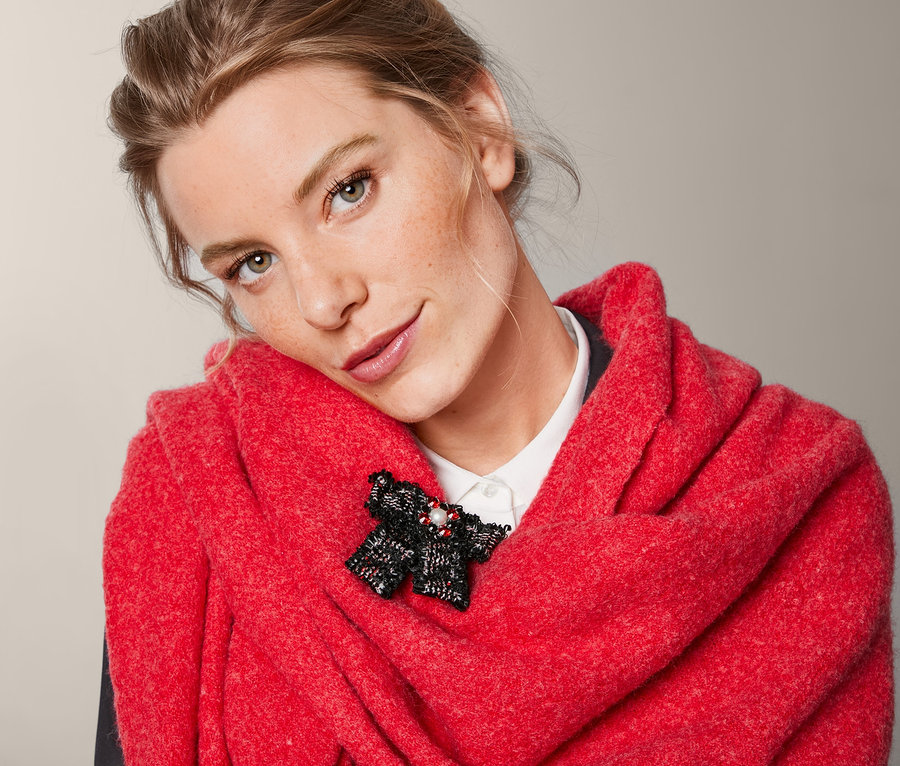 Frau mit rotem Schal und Schleifenbrosche aus Tweed.