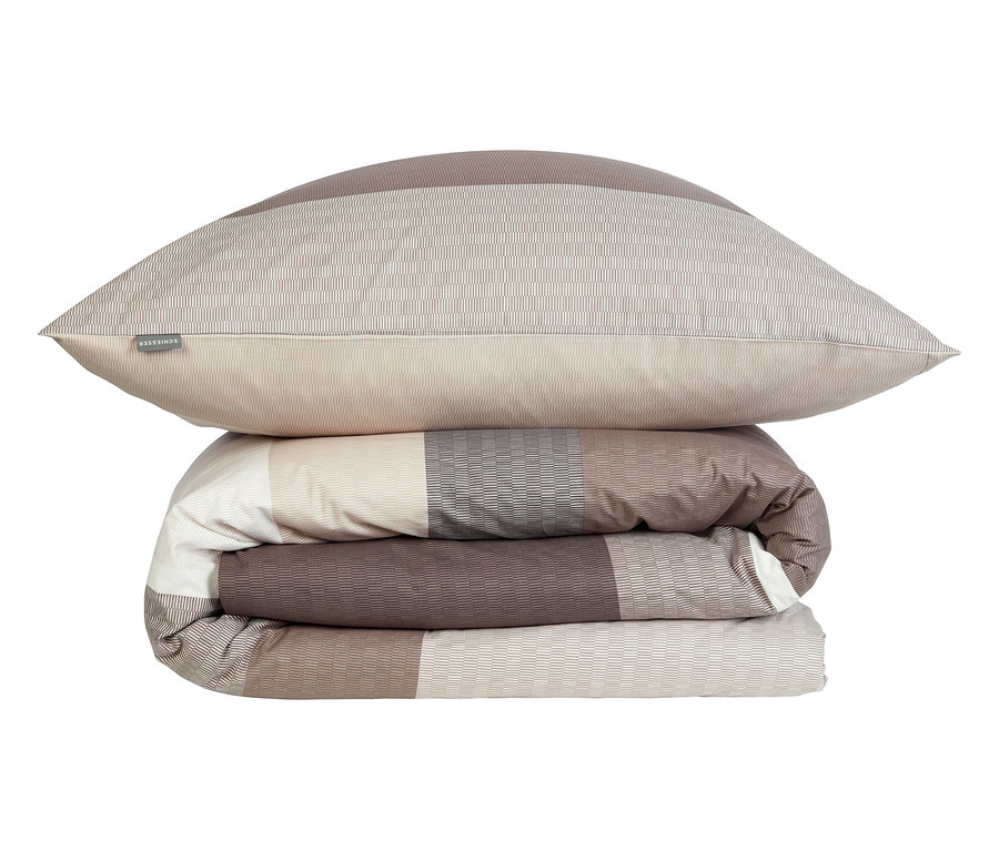 Ein gefalteter, beige-brauner Bettbezug mit einem Kissen oben drauf.