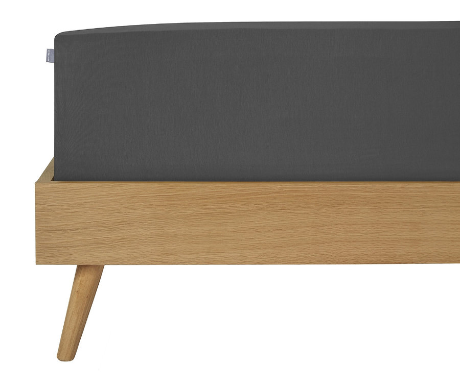Detailansicht eines grauen Spannbettlakens auf einem Holzbett.
