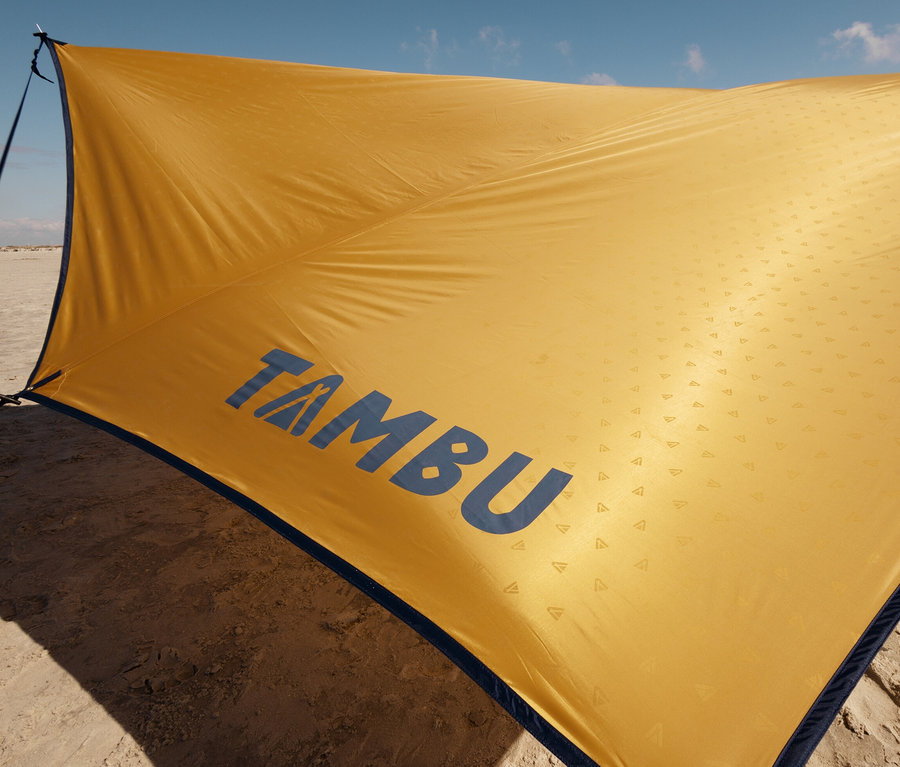 Gelbes Tambu Sonnensegel PALA, groß, an einem Sandstrand.