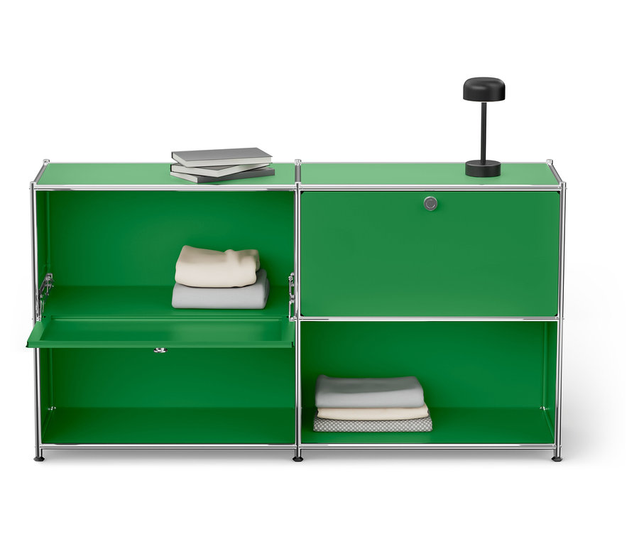 Grüner Schrank mit silbernem Rahmen mit zwei Regalen und Büchern, Lampe und gefalteter Kleidung.