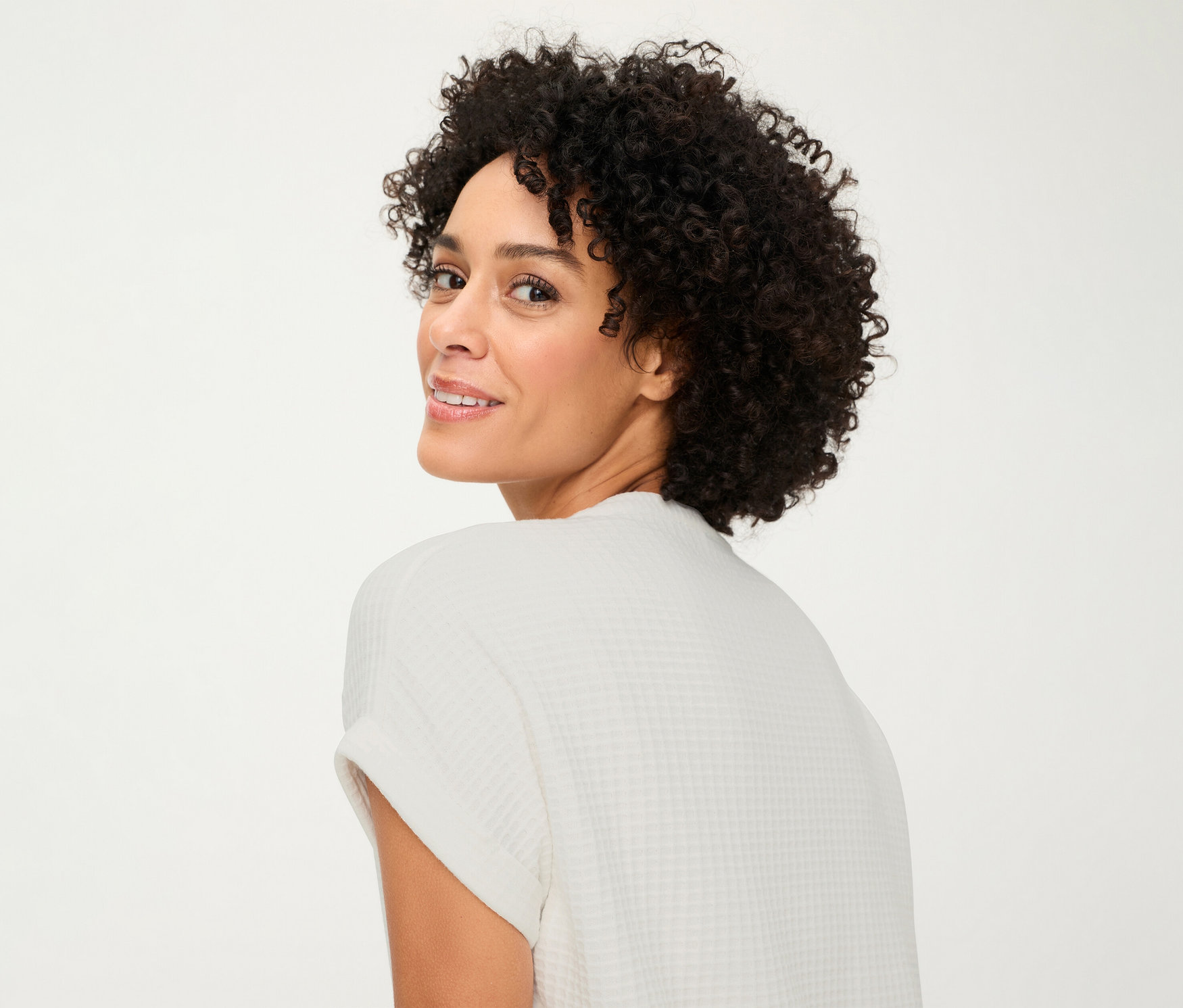 Frau blickt über ihre Schulter und trägt ein strukturiertes Olsen Shirt mit Knöpfen.