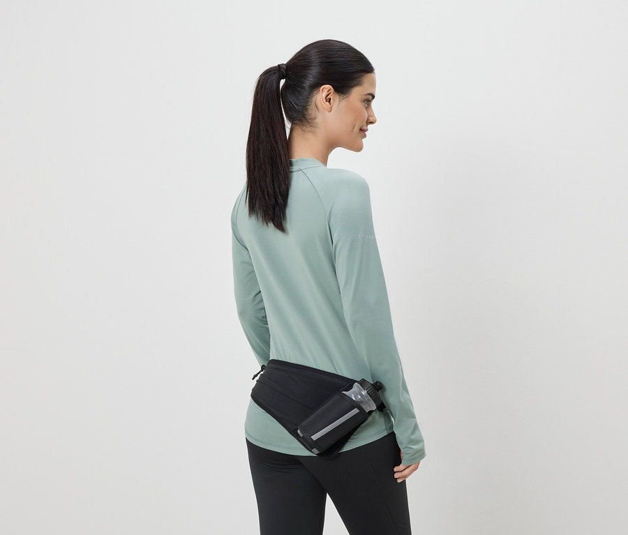 Frau in Sportkleidung mit schwarzer Gürteltasche und Trinkflasche von hinten gesehen.