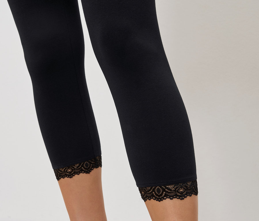 Nahaufnahme von Beinen, die schwarze Leggings mit Spitzenbesatz tragen.