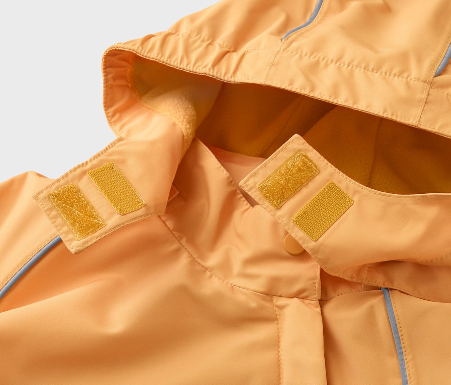 Nahaufnahme einer orangefarbenen Jacke mit Kapuze, die mit gelben Klettverschlüssen befestigt wird. Die Kapuze ist mit Fleece gefüttert.