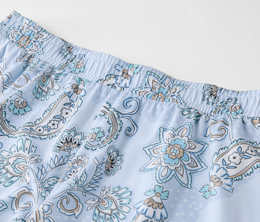 Detailansicht einer hellblauen Hose mit blauem Blumenmuster und elastischem Bund.