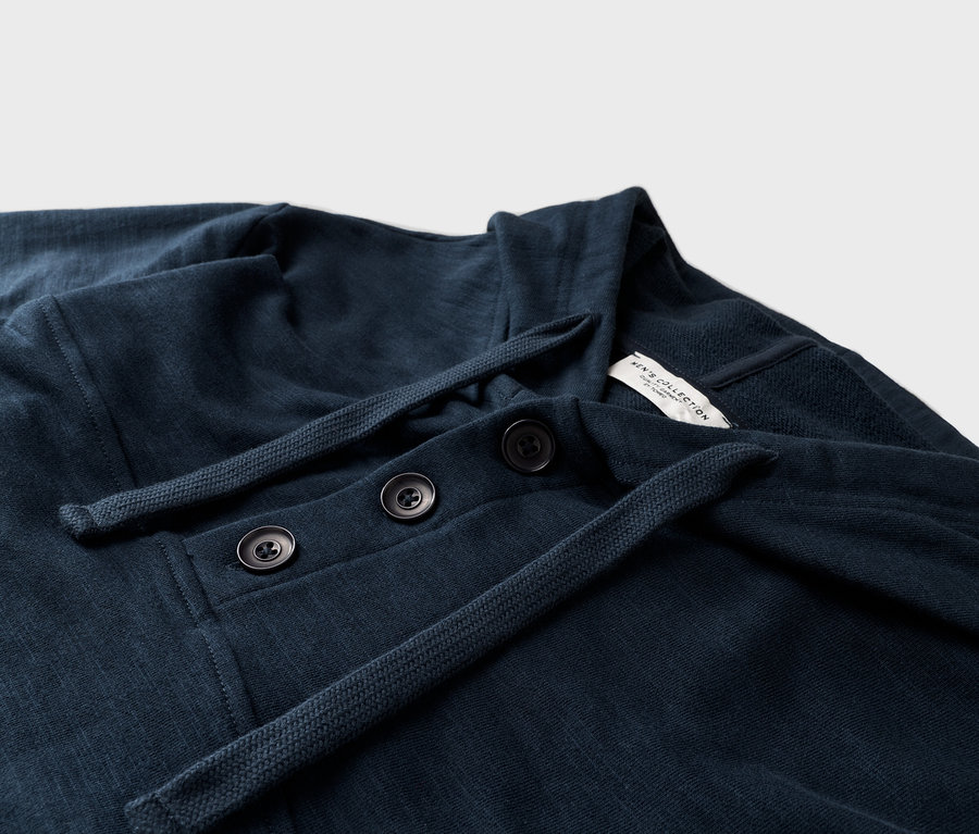 Nahaufnahme eines marineblauen langärmeligen Hemdes mit drei Knöpfen und Kordelzug.