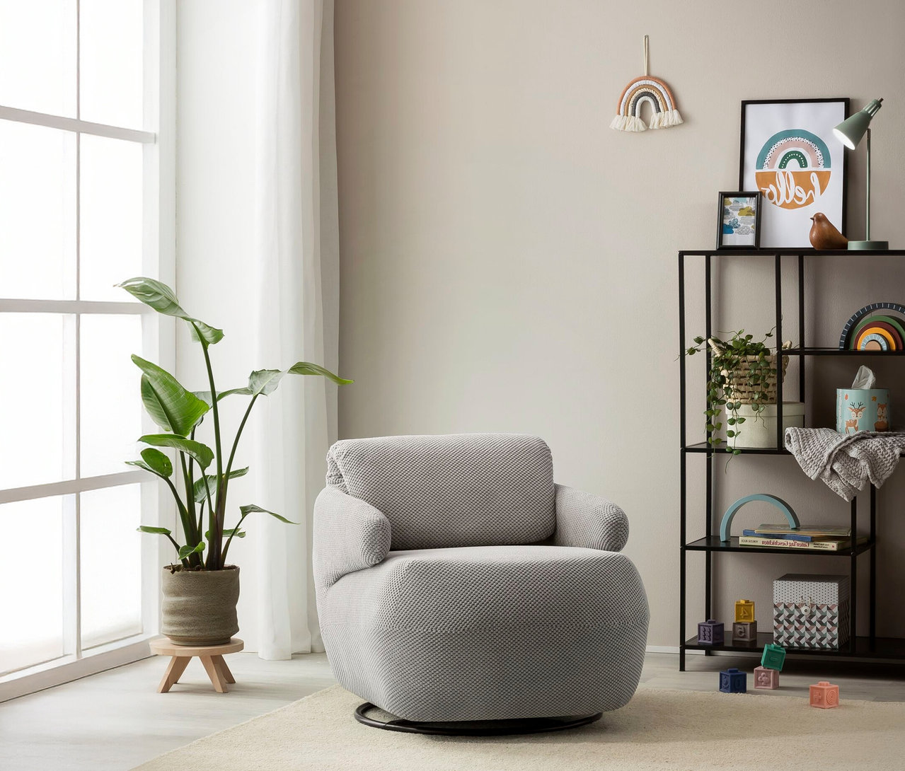 Ein grauer Domo Drehsessel »Valencia« mit Drehfunktion steht in einem hellen Raum neben einem Fenster und einem Regal.