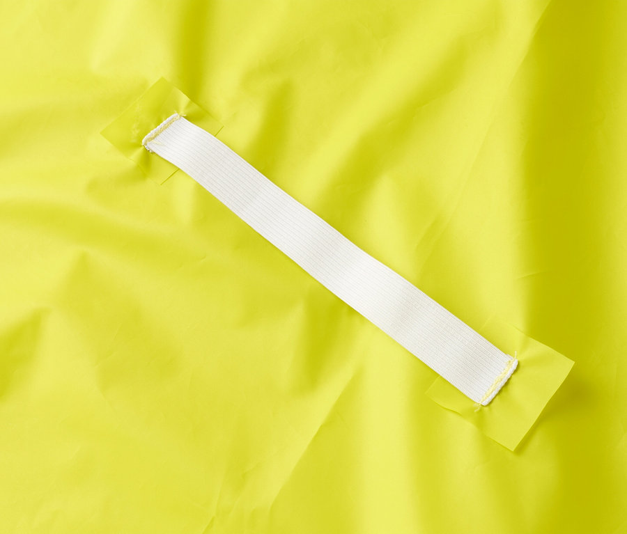 Nahaufnahme eines gelben Stoffes mit einem weißen Gummiband, das an zwei gelben Stoffstücken befestigt ist.