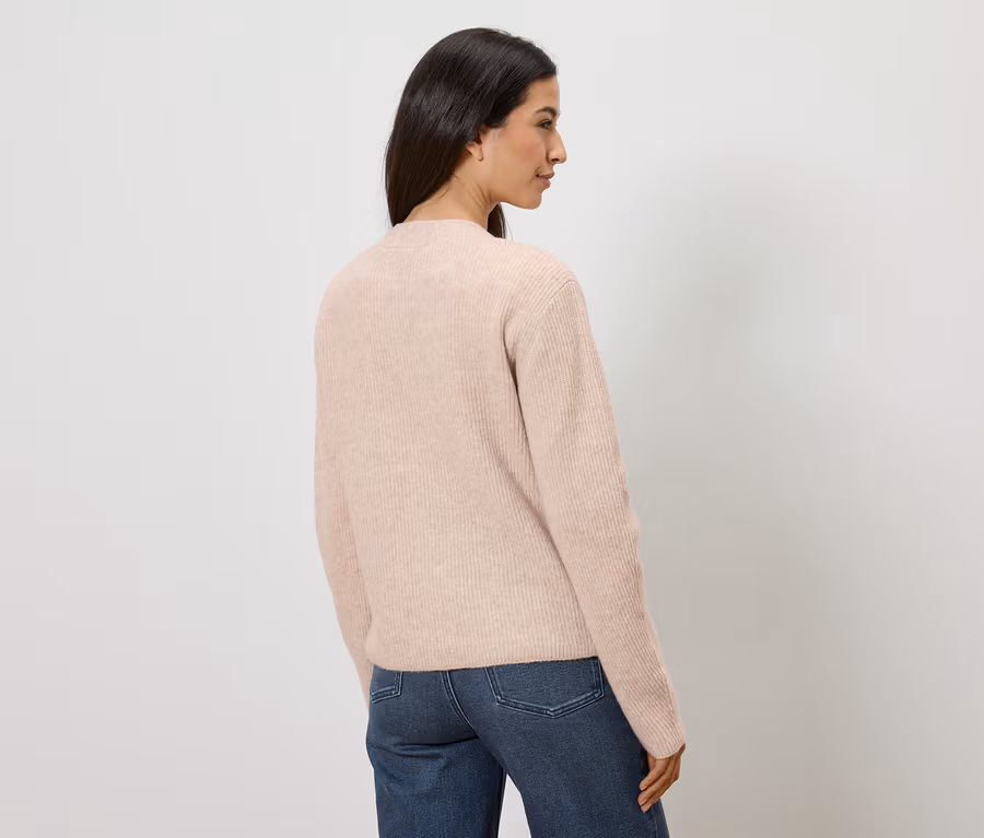 Frau von hinten in Jeans und rosafarbenem Pullover vor weißem Hintergrund.