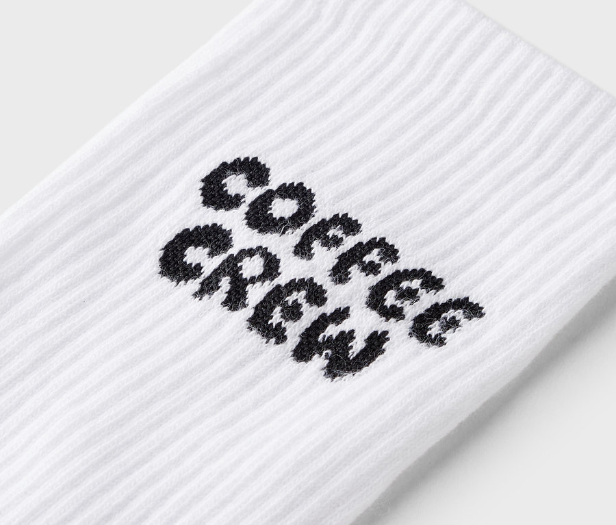 Nahaufnahme einer weißen Socke mit dem schwarzen Schriftzug "Coffee Crew".