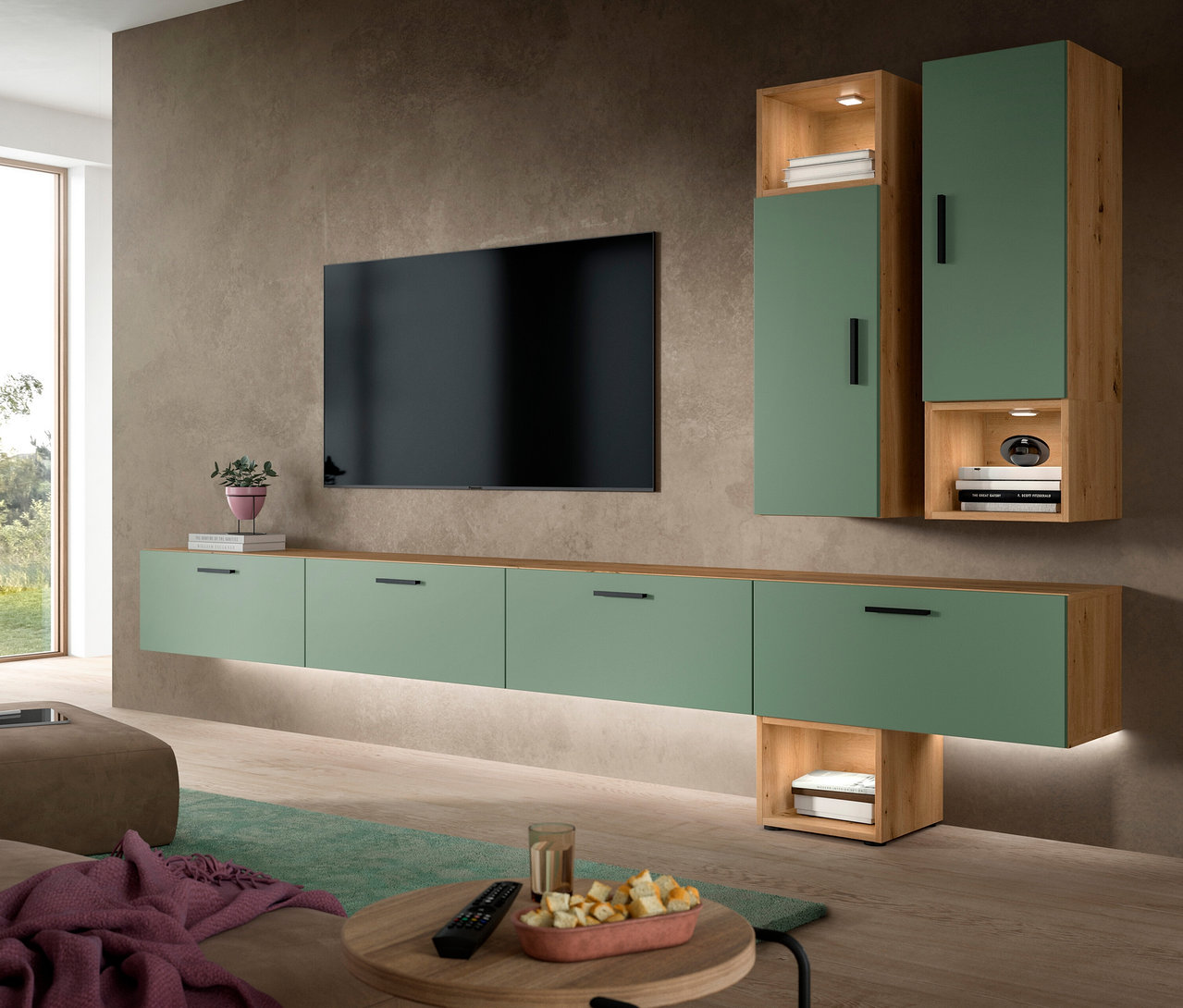 Eine xonox Wohnkombination »Only« in Grün und Holzoptik mit Beleuchtung, bestehend aus einem schwebenden Lowboard und Hängeschränken, unter einem Wandfernseher. Im Vordergrund steht ein Couchtisch mit Snacks.