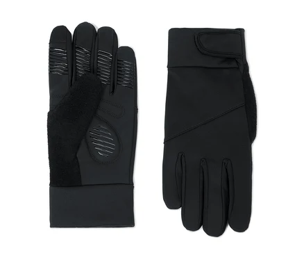 Zwei schwarze Handschuhe liegen nebeneinander auf weißem Hintergrund. Der linke Handschuh zeigt die Handfläche mit strukturierten Griffmustern an den Fingerspitzen und der Handfläche sowie einem weichen, flauschigen Daumenbereich. Der rechte Handschuh zeigt den Handrücken mit glatter Oberfläche, einem flauschigen Bereich an der Seite und einem verstellbaren Klettverschluss am Handgelenk.