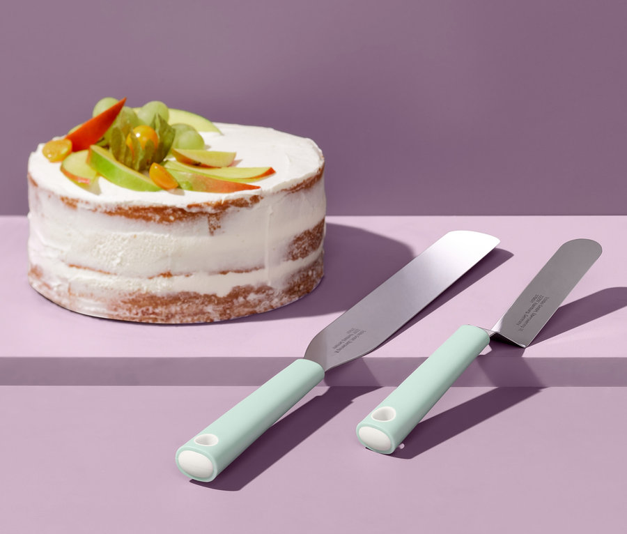 Zwei Streichpaletten liegen neben einem verzierten Kuchen.