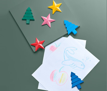 Kinderzeichnungen und 6 Wachsmalstifte auf grünem Hintergrund.