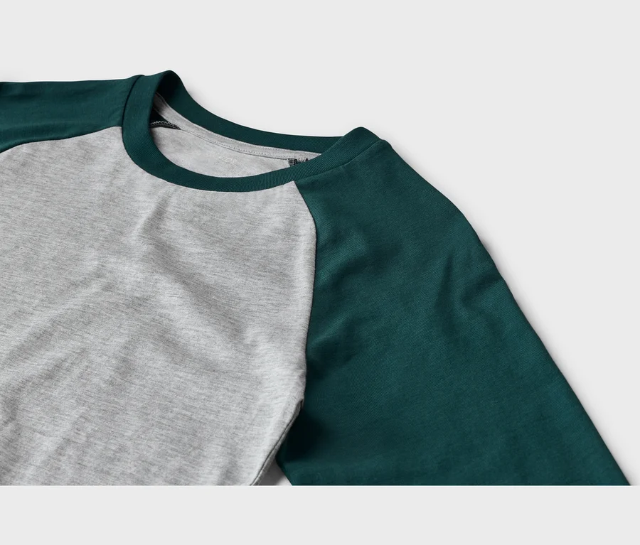 Nahaufnahme eines Langarmshirts mit grauem Rumpf und dunkelgrünen Raglanärmeln sowie einem dunkelgrünen Rundhalsausschnitt.