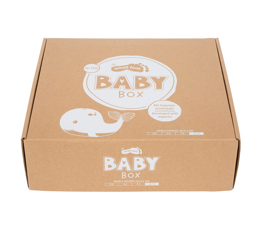 Brauner Karton mit weißem „small foot BABY BOX“-Schriftzug, einem Cartoon-Wal und dem Hinweis „Mit Experten entwickelt!“, Altersangaben 0-12 Monate.