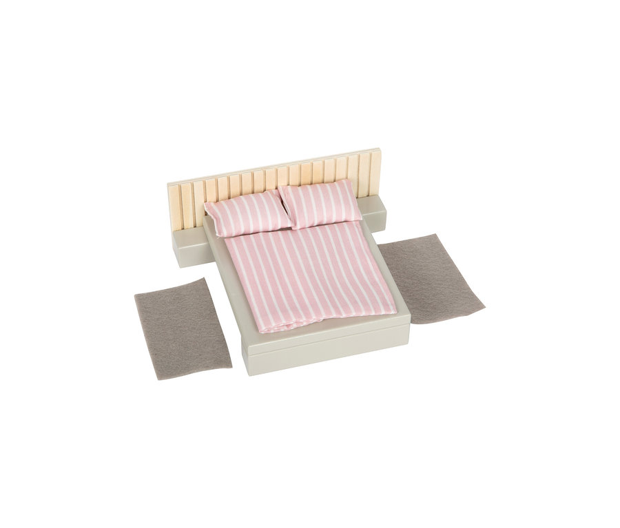 Ein kleines Bett aus dem small foot Puppenhausmöbel-Set mit rosa-weiß gestreifter Bettwäsche, einem Holz-Kopfteil, zwei grauen Nachttischen und zwei grauen Teppichen.