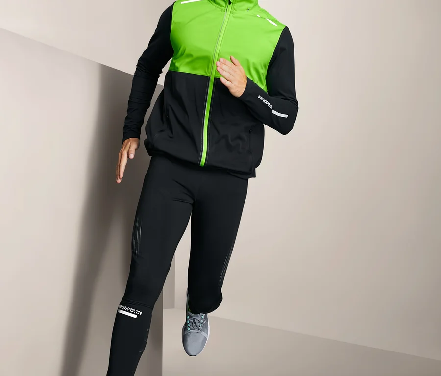 Mann mit neon-grüner Mütze und Softshell-Funktionsweste beim Laufen.