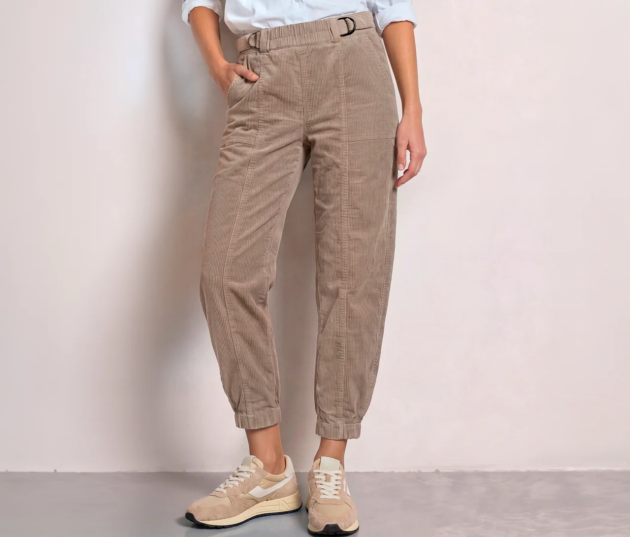 Eine Person trägt eine beigefarbene Street One Cordhose mit elastischem Bund, D-Ring-Schnalle und seitlichen Taschen, dazu helle Sneaker.