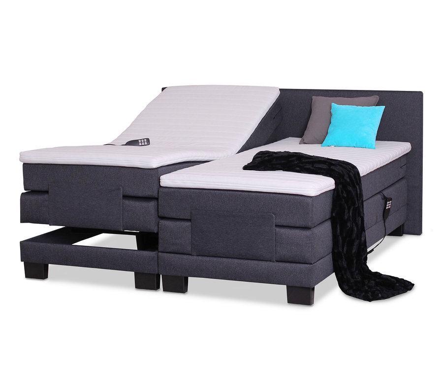 Detailansicht eines motorisch verstellbaren Bettes. Eine Seite ist hochgefahren, auf dem Bett liegen eine Fernbedienung, ein graues und ein türkisfarbenes Kissen sowie eine schwarze Decke. sun garden Boxspringbett mit motorischer Verstellung, 180 x 200 cm