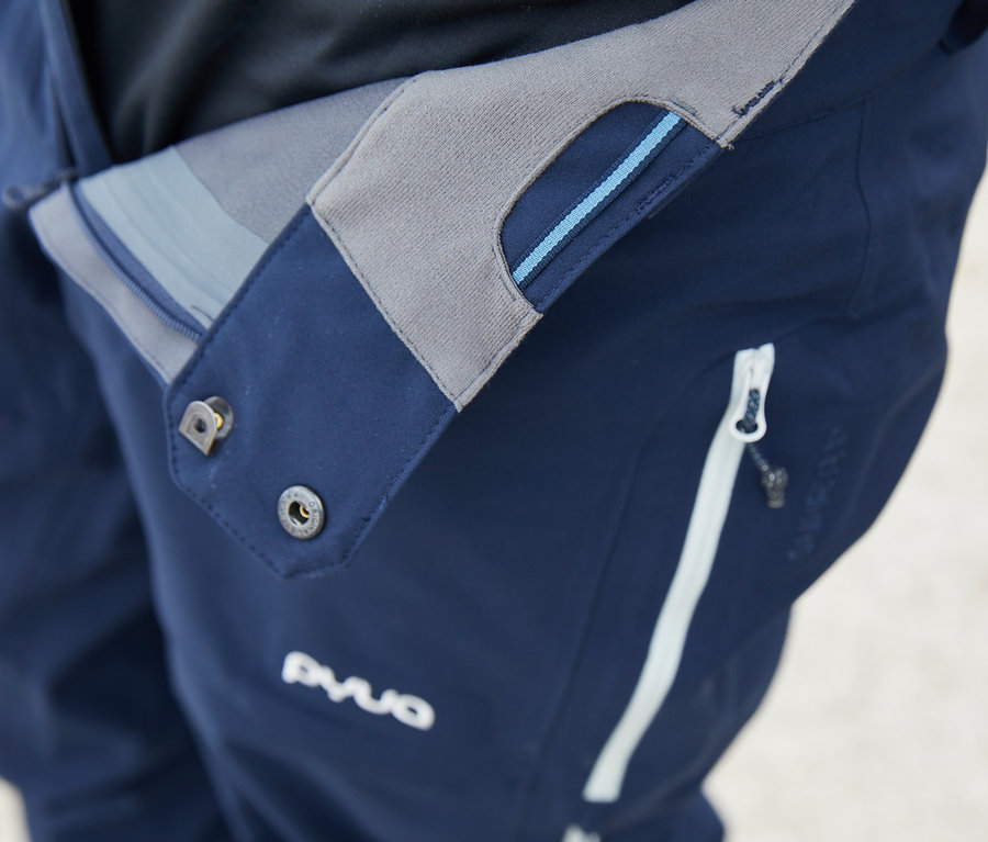 Detailaufnahme einer blauen High-End-Skihose »PYUA« mit weißem Reißverschluss.