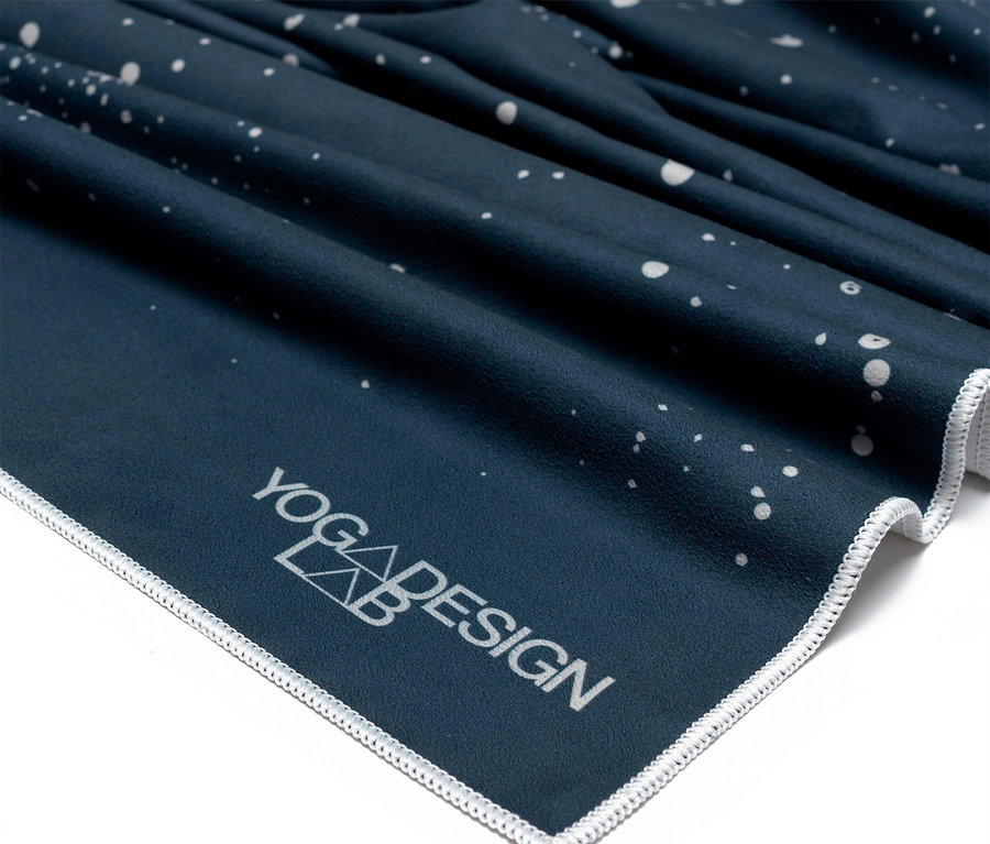 Detailaufnahme einer Ecke einer dunkelblauen Yogamatte mit weißem Aufdruck und Saum.