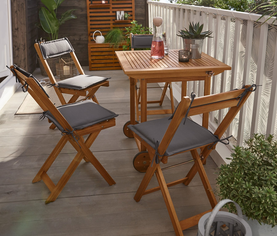 Auf einer Terrasse steht ein klappbares Balkon-Set mit einer LED-Filament-Outdoor-Lichterkette. Im Hintergrund befindet sich eine Balkon-Sichtschutzbank.