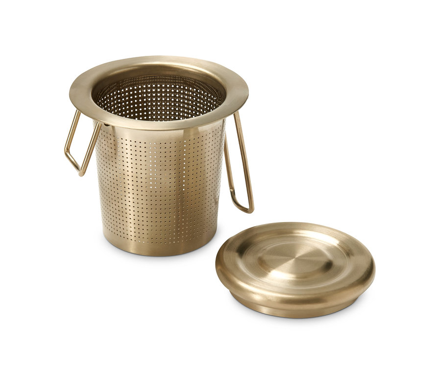 Goldenes Teesieb und Deckel auf weißem Hintergrund.
