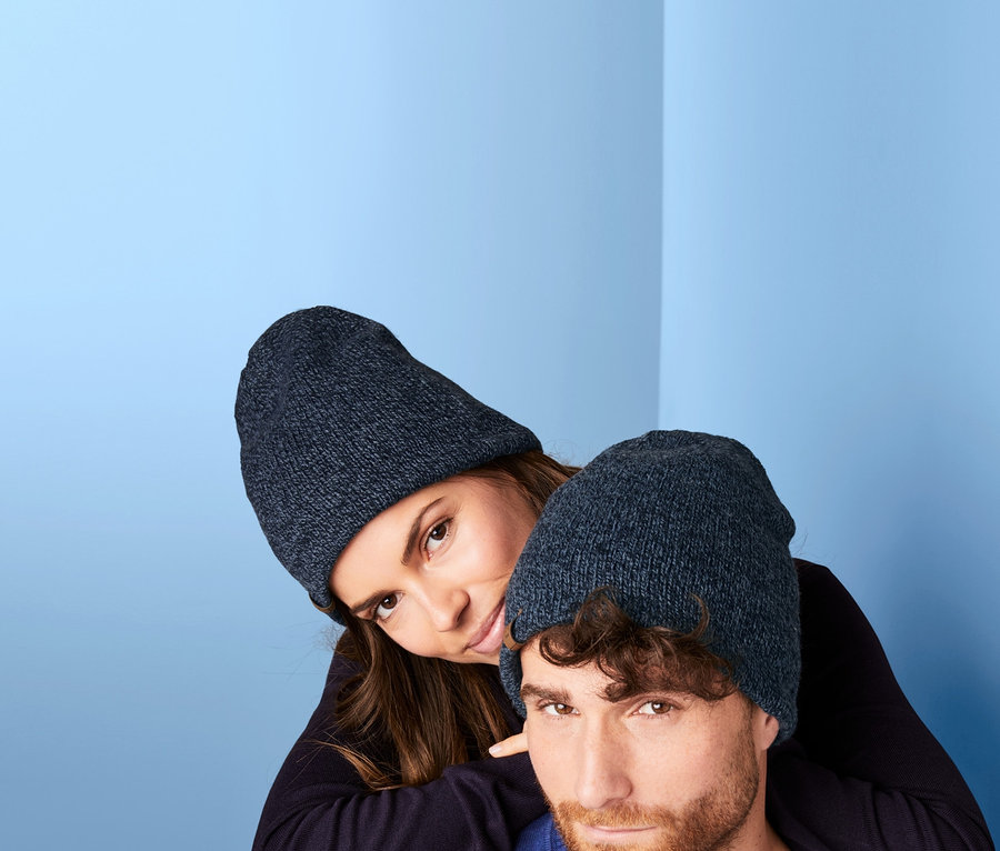 Frau lehnt an Mann, beide tragen eine Thermo-Strickmütze.