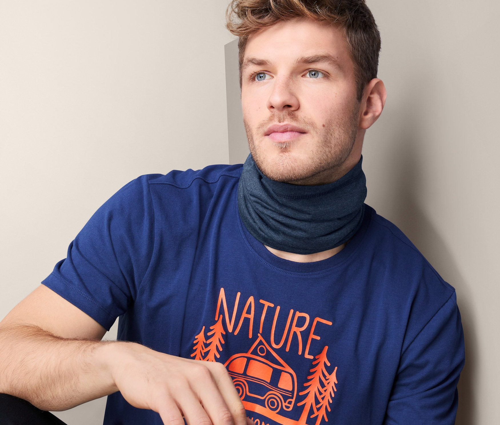 Mann trägt dunkelblau meliertes Multifunktionstuch und T-Shirt mit Aufdruck.