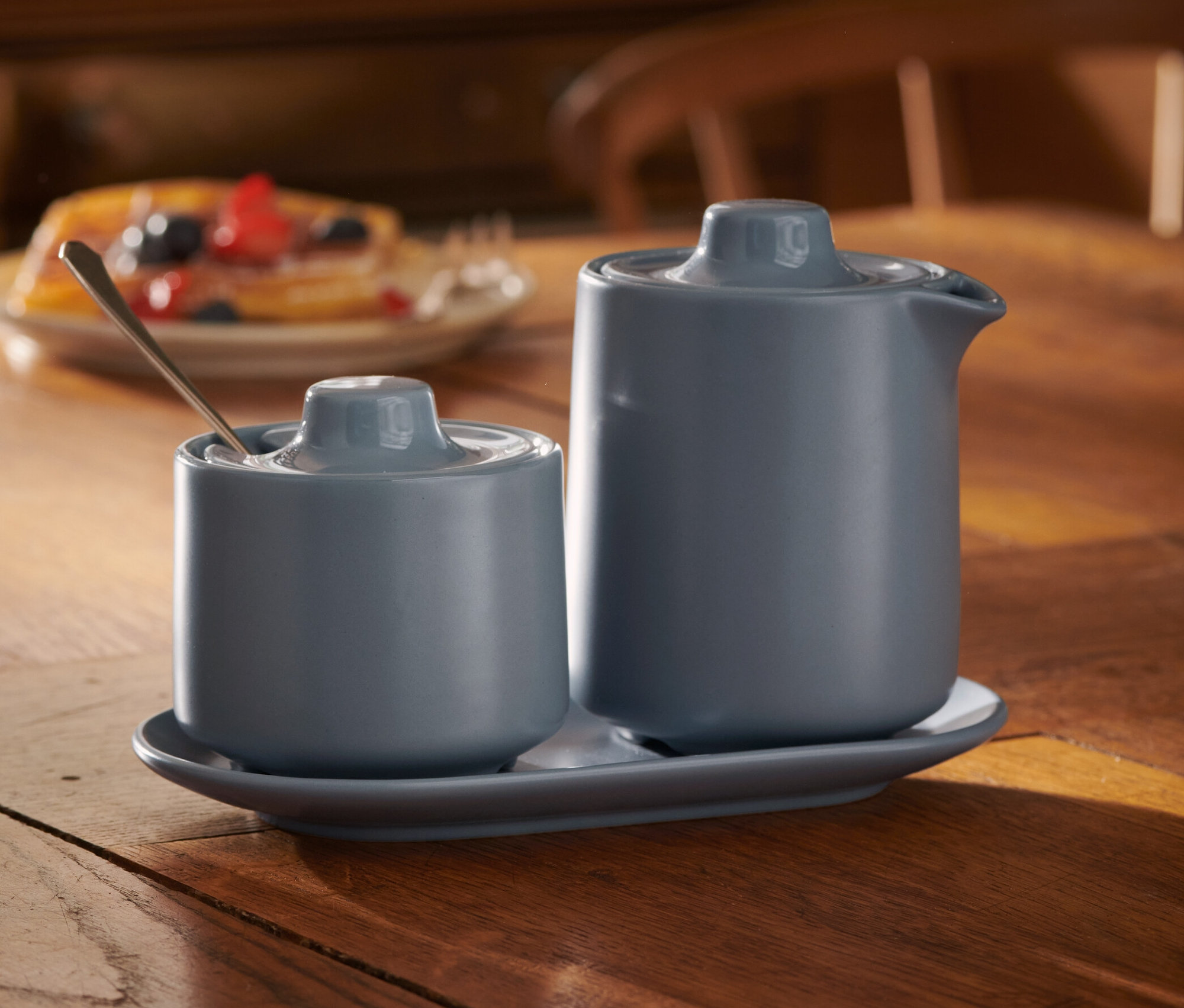 Blaues Milch- und Zuckerset auf Holztisch.