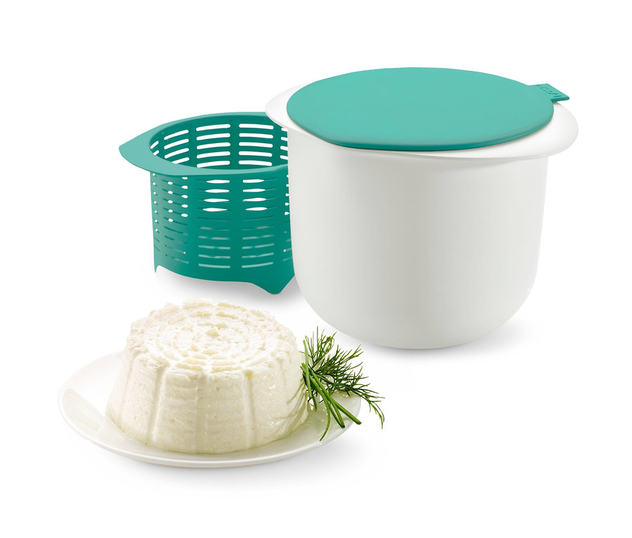 Frischkäsebereiter-Set mit weißem Behälter, grünem Deckel und Sieb sowie fertigem Käse auf einem Teller.