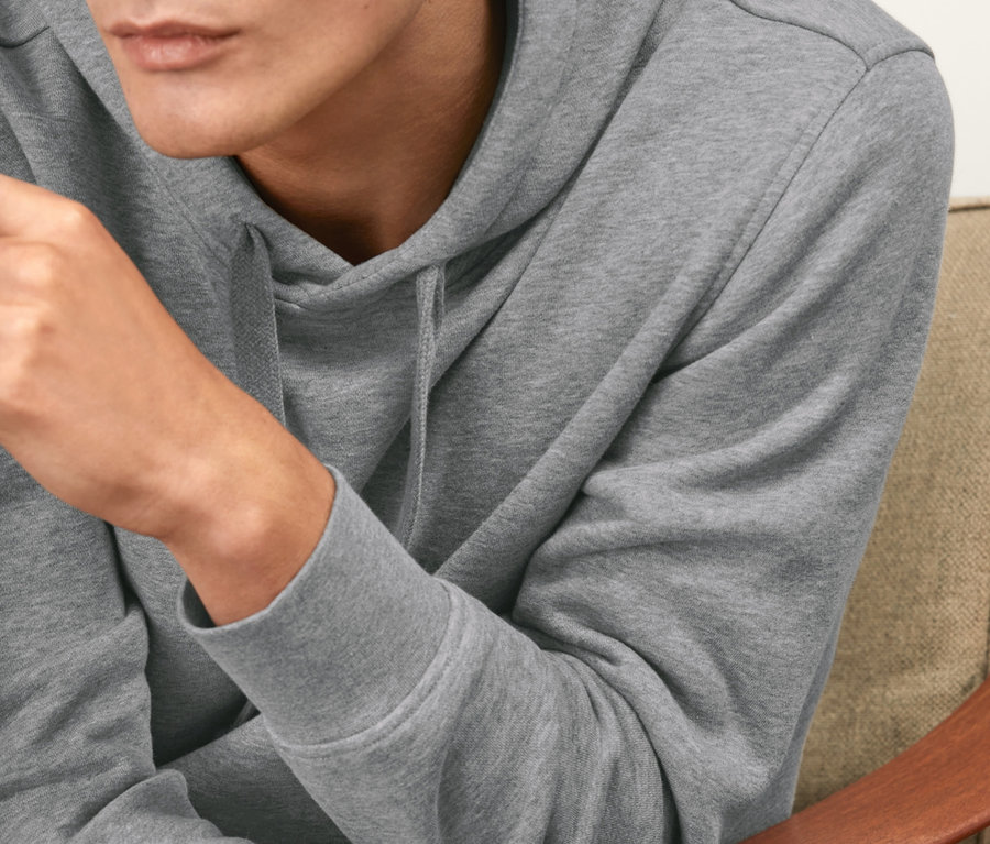 Mann sitzt im Sessel und trägt einen grauen Hoodie.