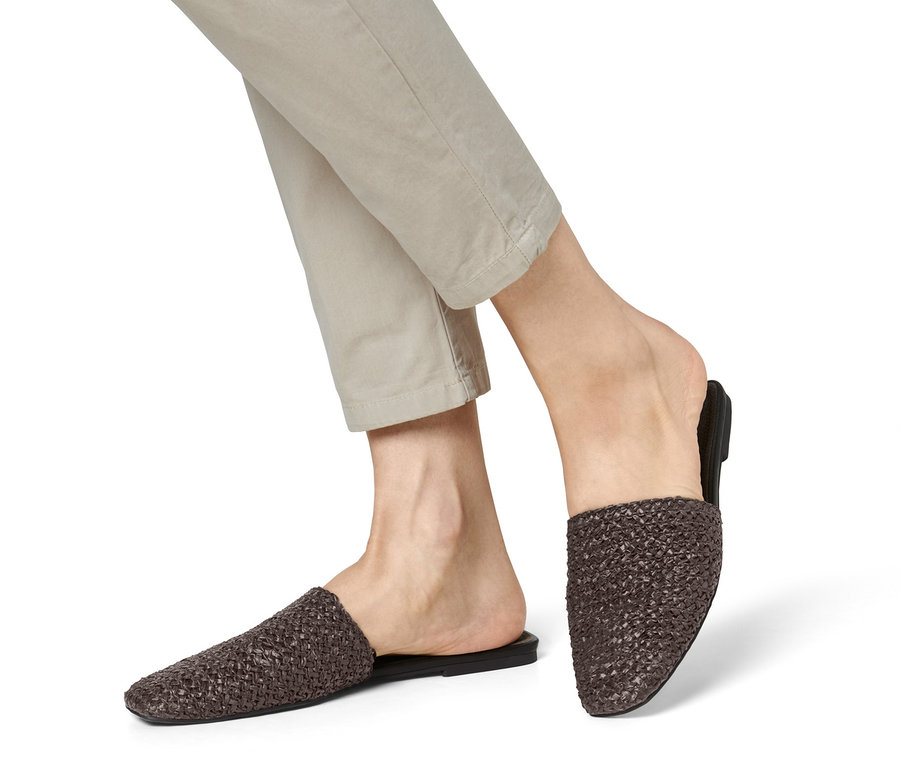 Beine in beigen Hosen und Mules.