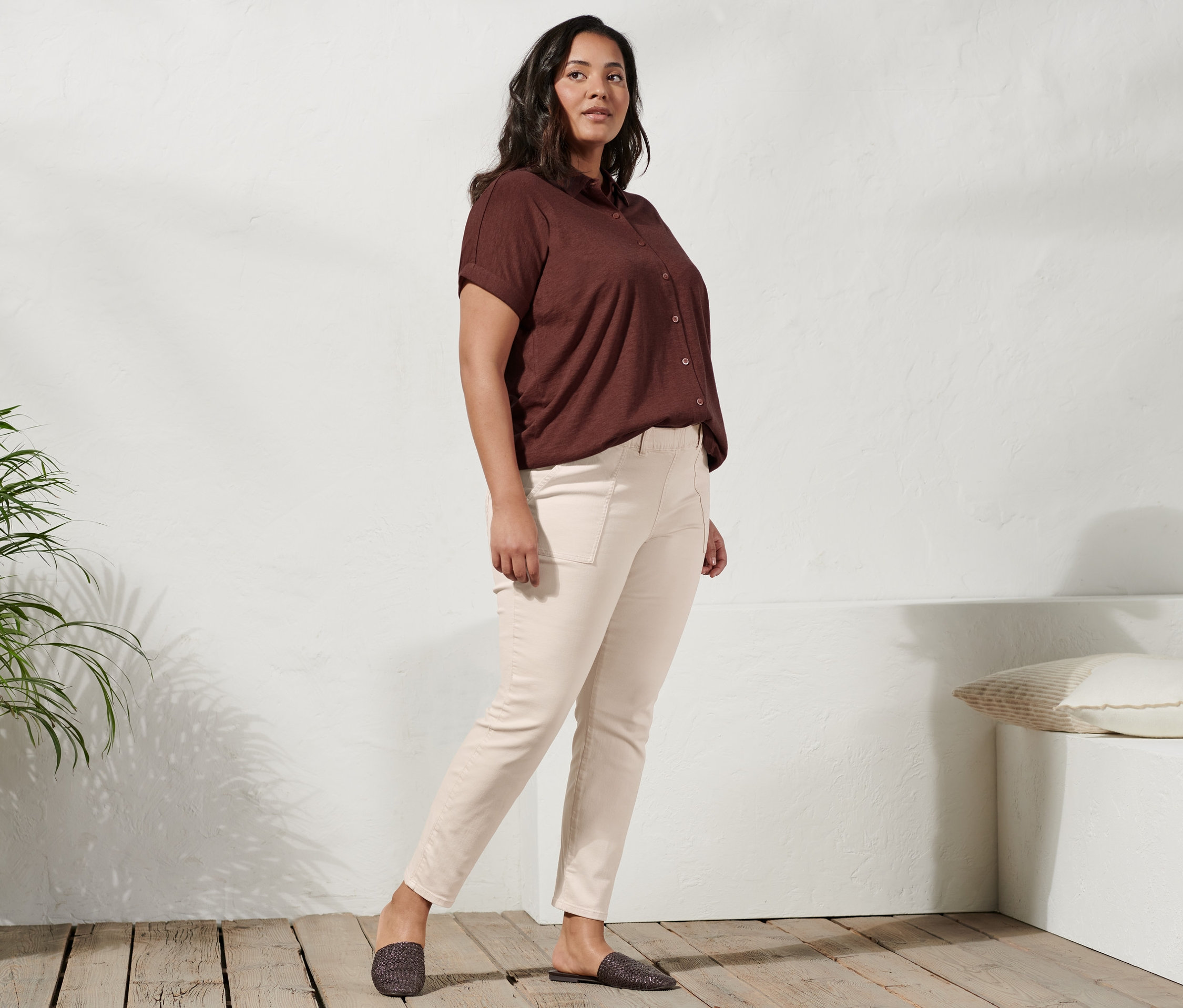 Frau posiert in Mules, Treggings und Blusenshirt mit Knopfleiste.