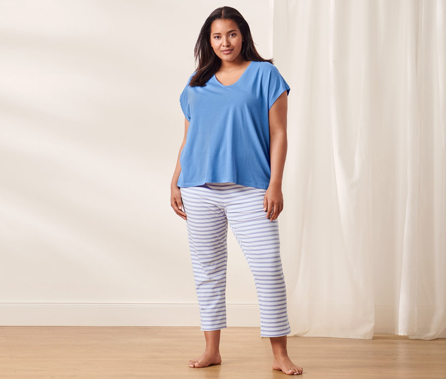 Frau steht und trägt einen blauen Pyjama.