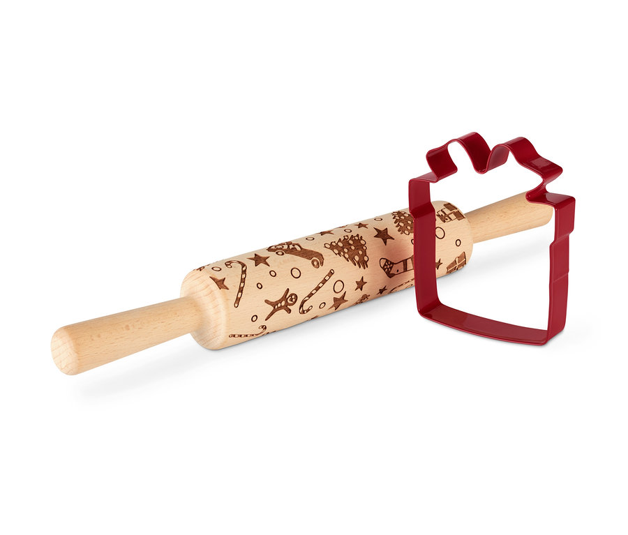 Eine Motiv-Teigrolle liegt neben einem roten, Geschenk-förmigen Ausstecher.