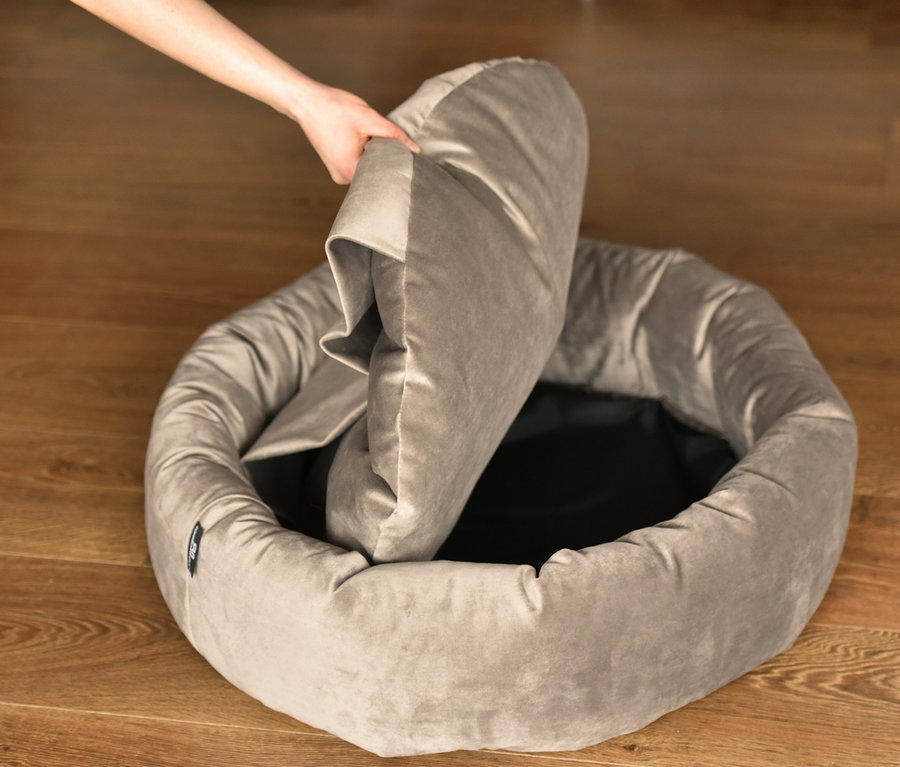 Eine Hand platziert ein graues Kissen in ein graues rundes Kuschelinsel »Lajos«.