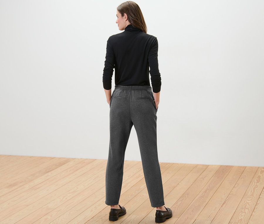 Frau von hinten trägt ein schwarzes Langarmshirt und graue Joggpants.