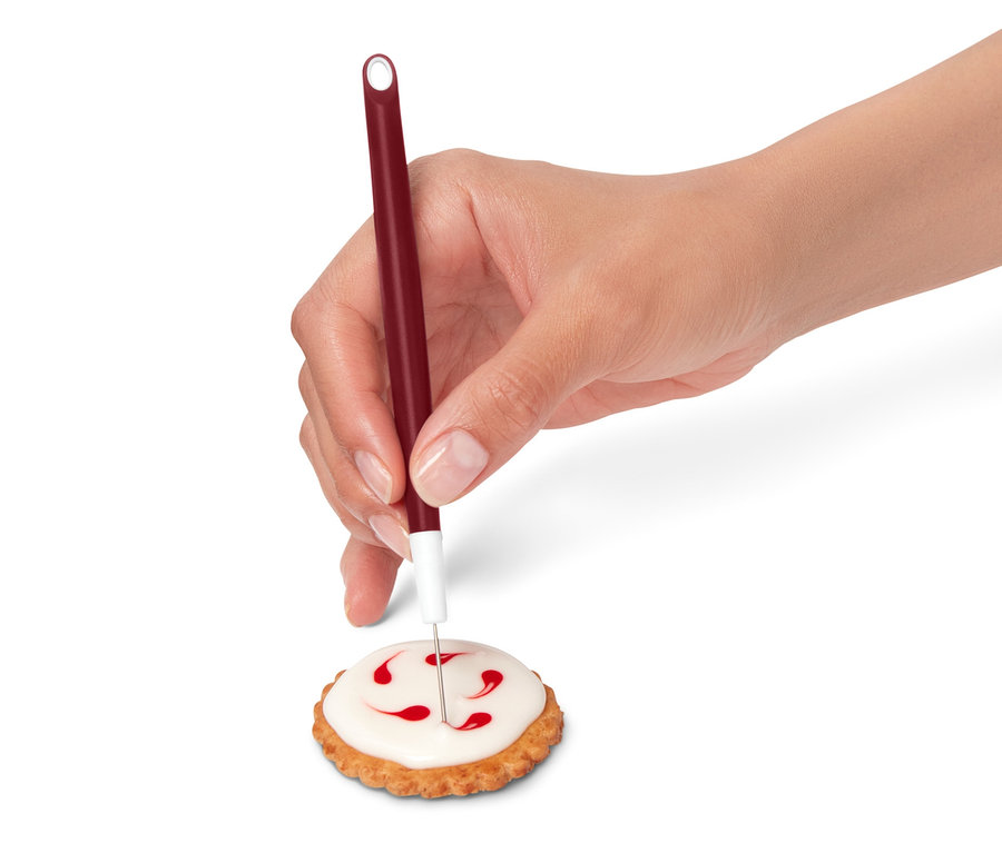 Eine Hand verziert einen Keks mit Zuckerguss aus einem Royal-Icing-Set.