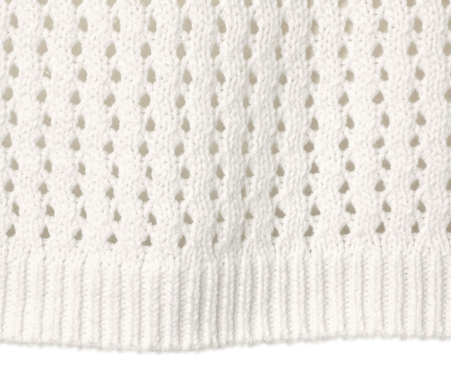 Detailansicht eines weißen Pullovers in Pointellestrick.